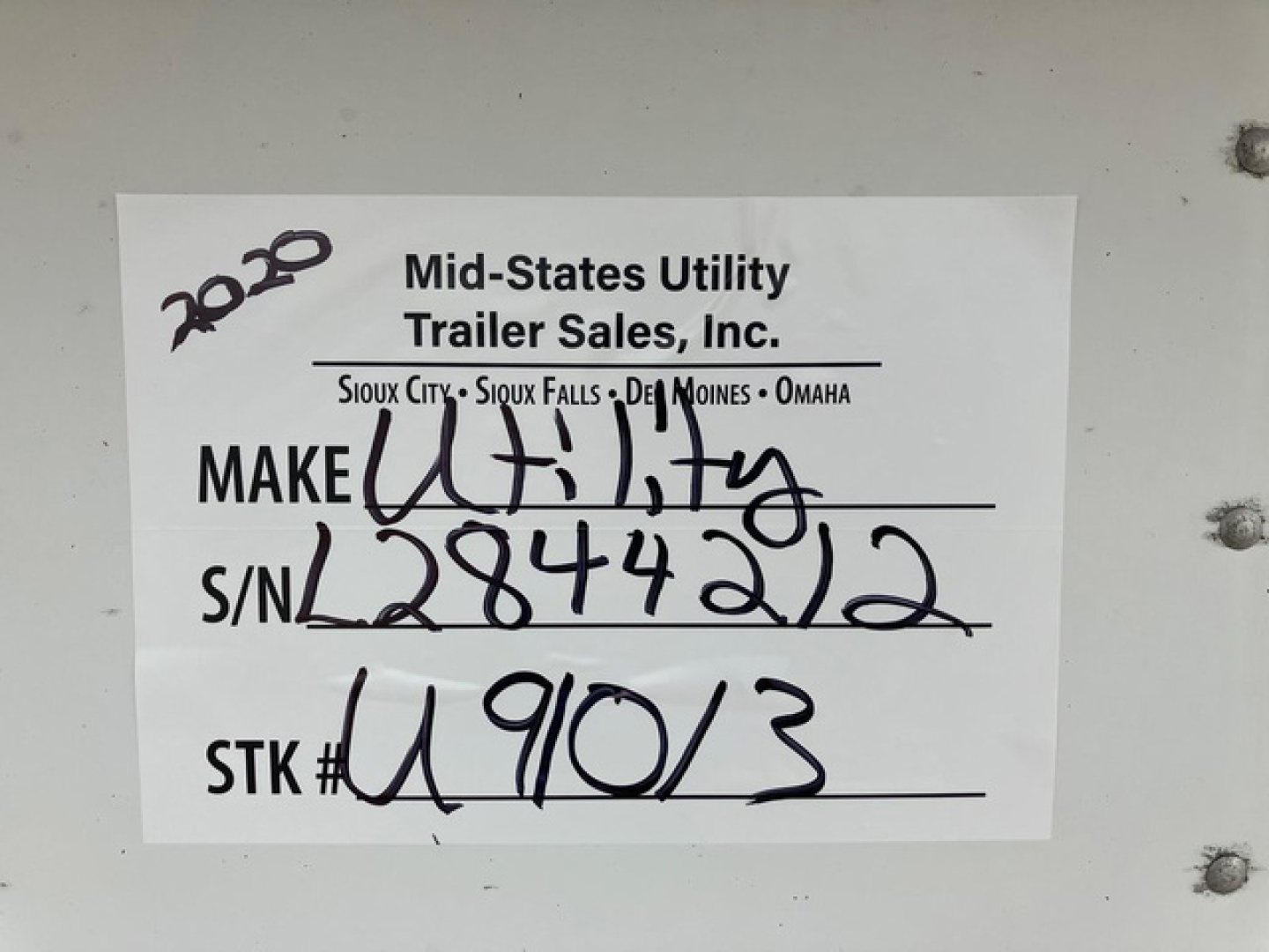 A white label on a trailer with handwritten stock number S/N 2844212 and STK # U9103, from Mid-States Utility Trailer Sales, Inc. It lists 2020 and locations Sioux City / Sioux Falls / Omaha / DE(s) Moines.