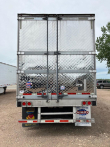 Rear view of a 2020 Utility refrigerated trailer with diamond plate metal doors, dual rear doors, and various stickers including state and dealer labels.