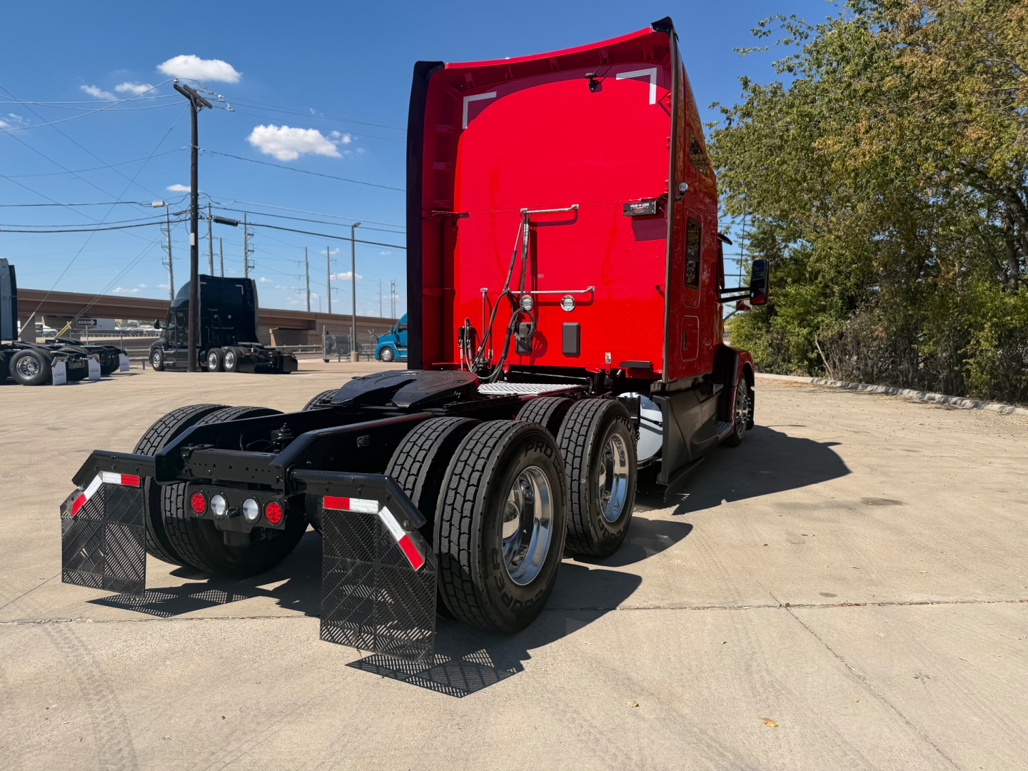 Kenworth T680 tractor rear view showing triple axles and mud flaps with reflective chevrons.