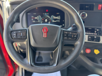Kenworth T680 steering wheel with multifunction controls and dashboard display visible in the background.