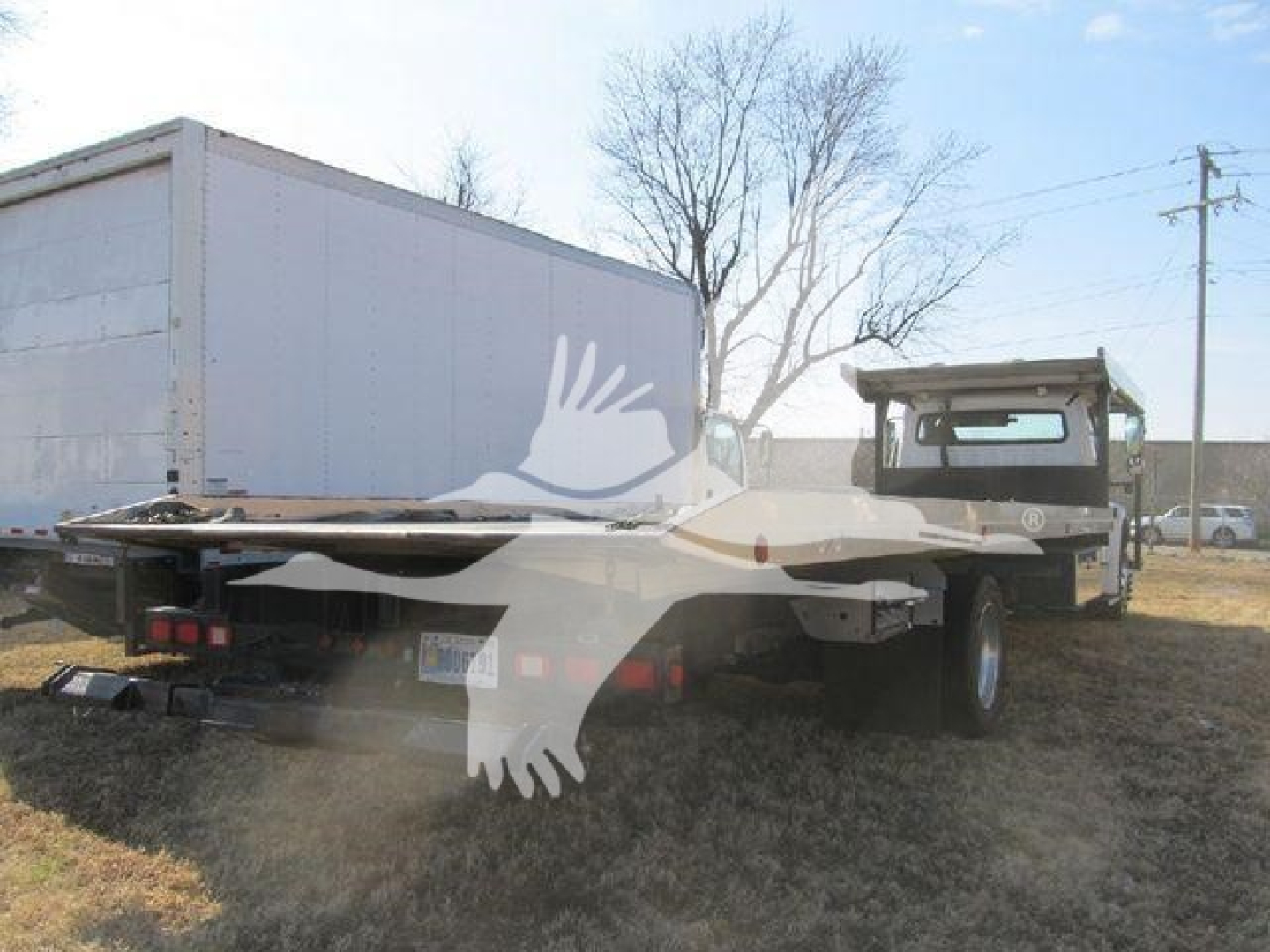 Freightliner M2 106 auto carrier truck viewed from rear-left showing flatbed carrier bed and forklift-style ramps.