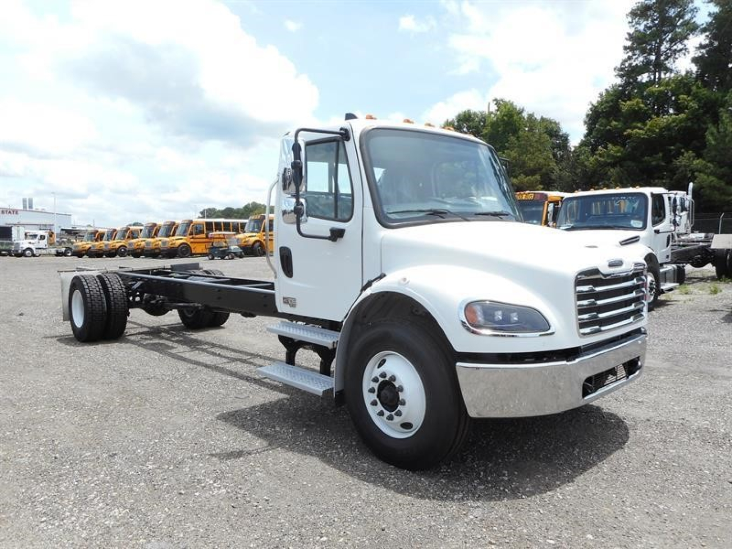 Freightliner M2 106 cab chassis in white, front-right view, no cargo body, chassis rails visible with wheel, side steps and cab mirrors.