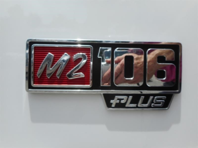 Freightliner M2 106 badge emblem on white truck tailgate showing M2 106 PLUS.