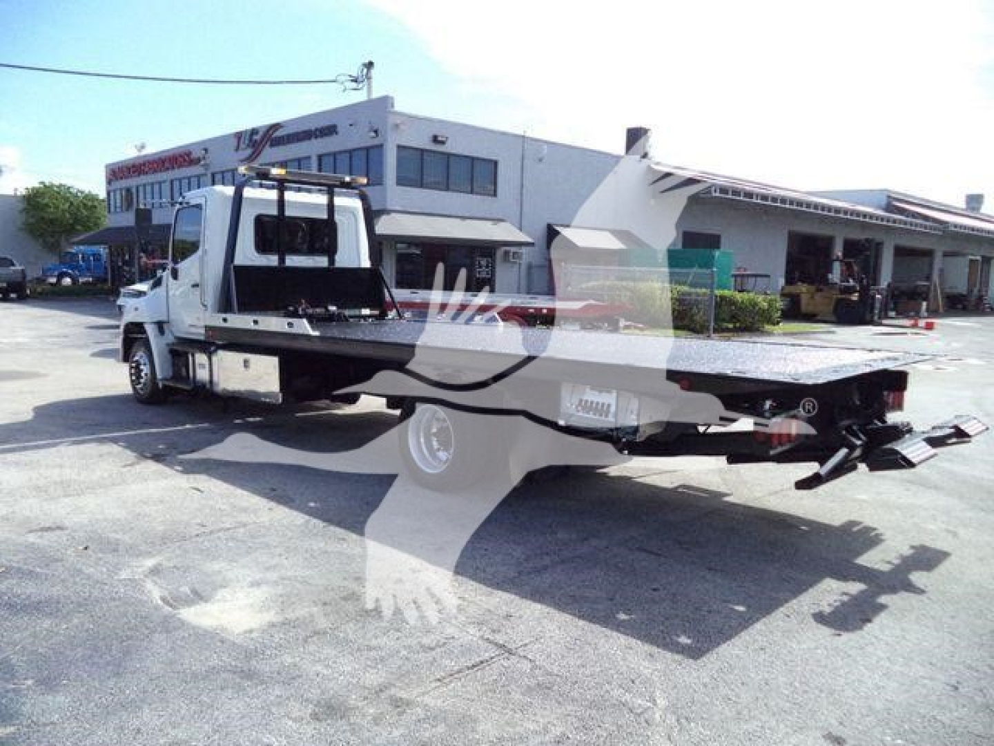 Truck from rear-left side showing rollback bed and towing equipment on a white Hino 258Al chassis.