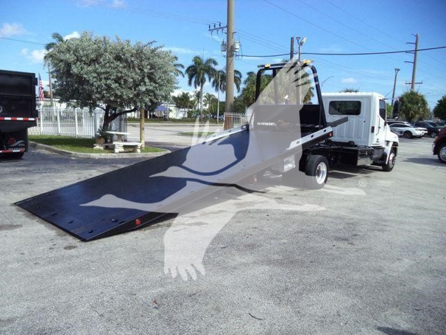 Hino 258Alp rollback tow truck with a low-flatbed tilted in a lot