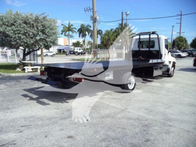 Flatbed tow truck from rear three-quarter view showing long flatbed, white cab, and dual rear wheels.