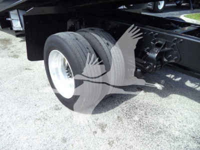 Truck rear dual wheels and suspension components in the chassis area of a 2020 Hino 258Al rollback truck showing front axle and frame.
