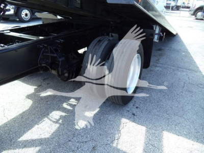 Trucks/roller bed showing rear dual wheels and suspension under a rollback truck, with part of the hydraulic bed and frame visible.