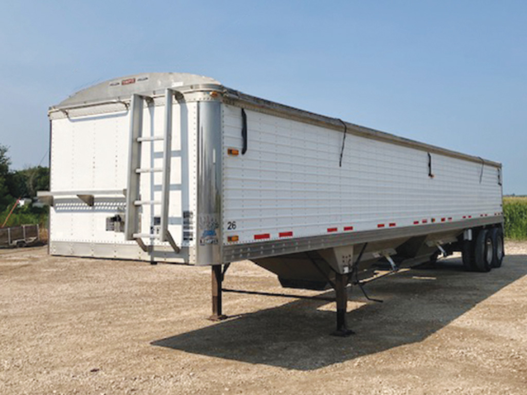 Trailer showing a Timpte Super Hopper with a tall rear ladder, white aluminum body, reflective tape along the sides, and a raised landing gear.