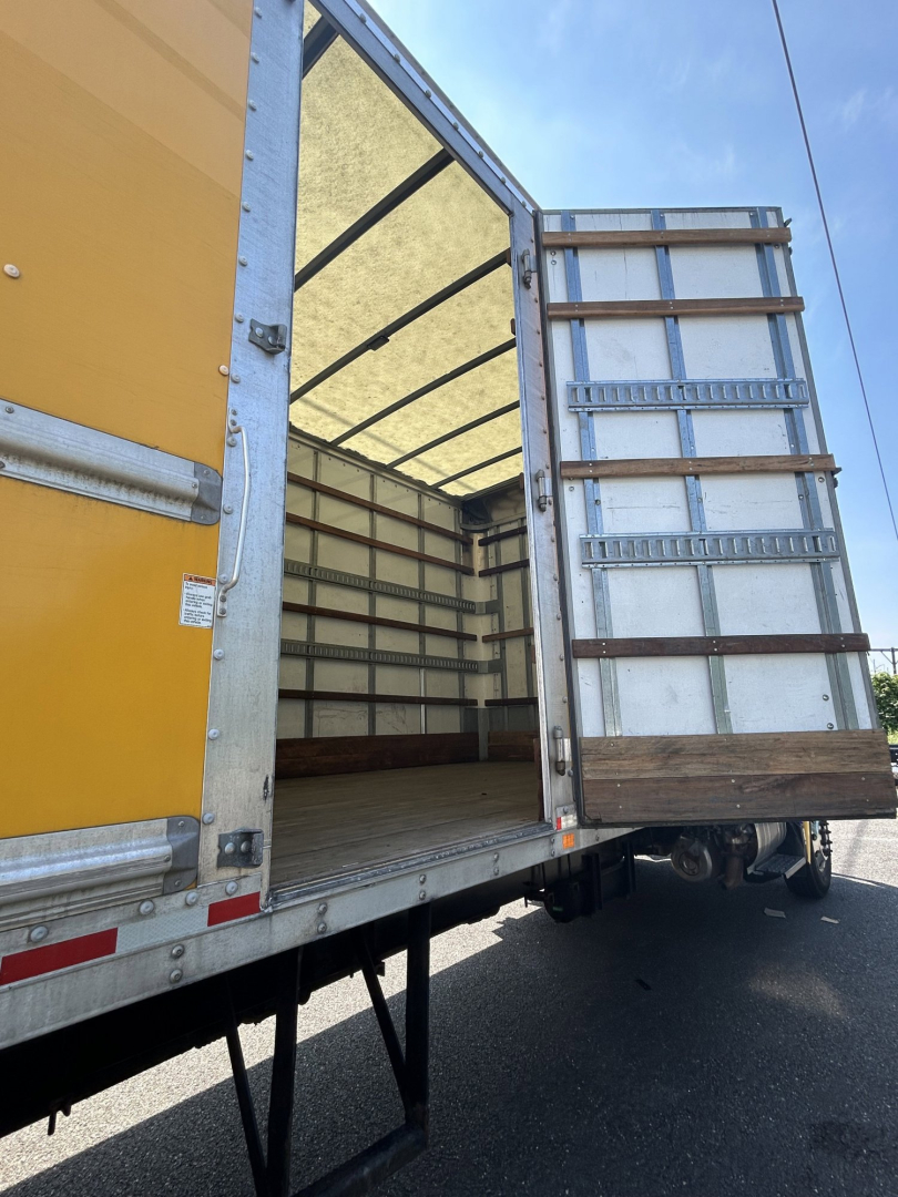 Truck cargo area open on 2020 Hino 338 showing box van interior and rear doors with metal framework and wooden floor.