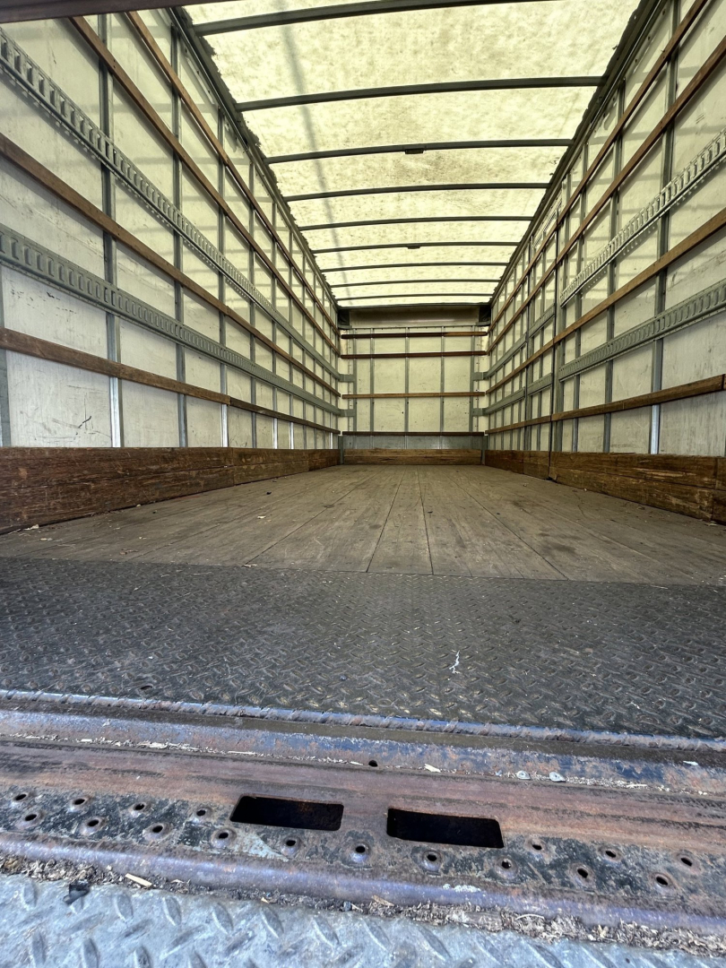 Truck cargo space of a 2020 Hino 338 with empty box, metal floor, side walls with horizontal support rails.
