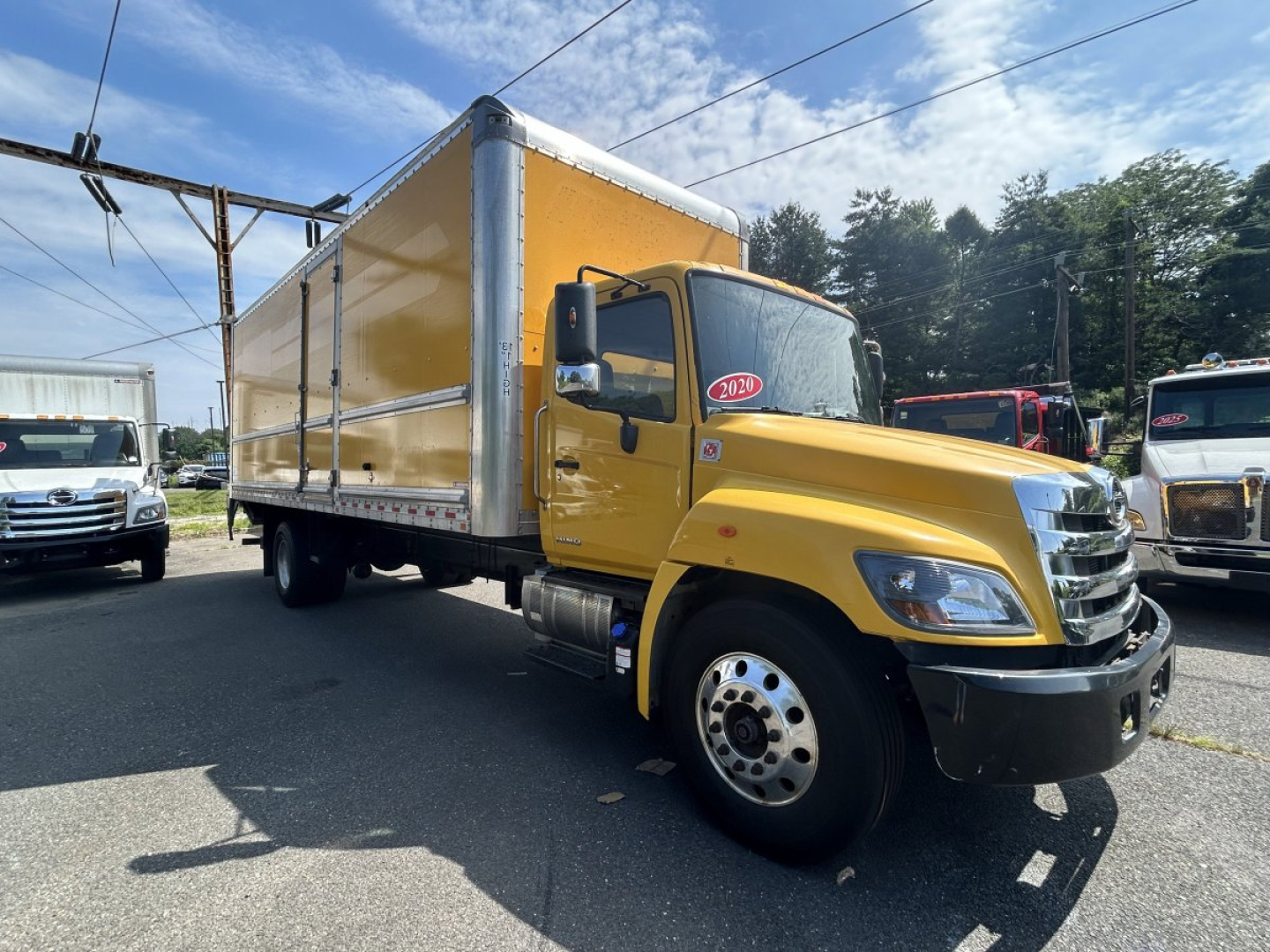 Box van truck showing a yellow Hino 338 with a large cargo box, side view, 2020 model year badge on windshield.