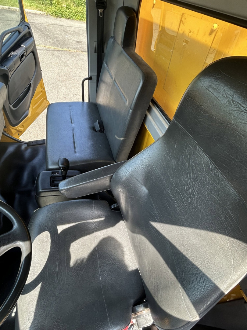 Cab interior of a 2020 Hino 338 box van showing driver seat and passenger seat with gear shifter visible.