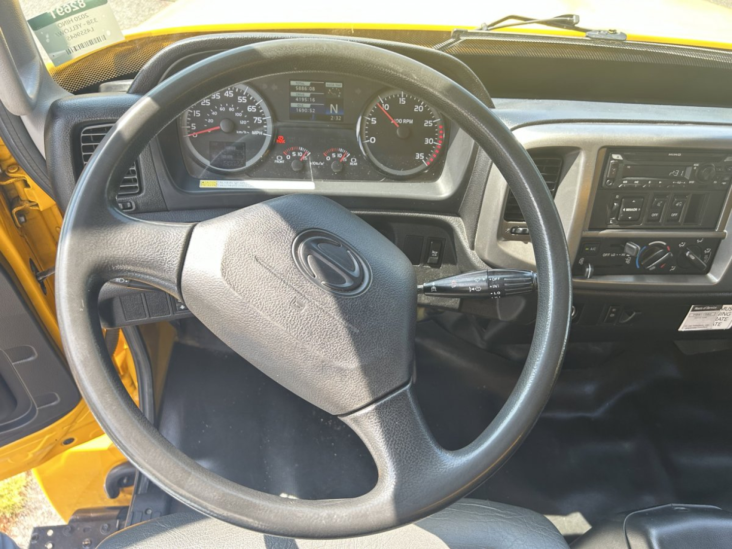 Dashboard and steering wheel of a 2020 Hino 338 box van truck interior showing steering wheel, instrument cluster, and center console.