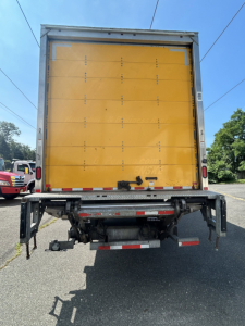 Rear view of a 2020 Hino 338 box van truck showing yellow cargo area with rear doors and chassis detail.