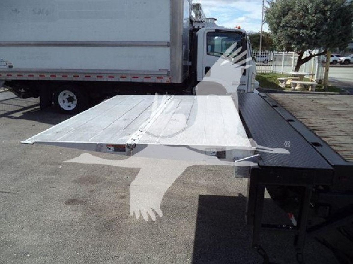 Flatbed truck loading ramp extended from a durastar 4300 chassis showing a metal ramp with screws and hinge by the flatbed edge.