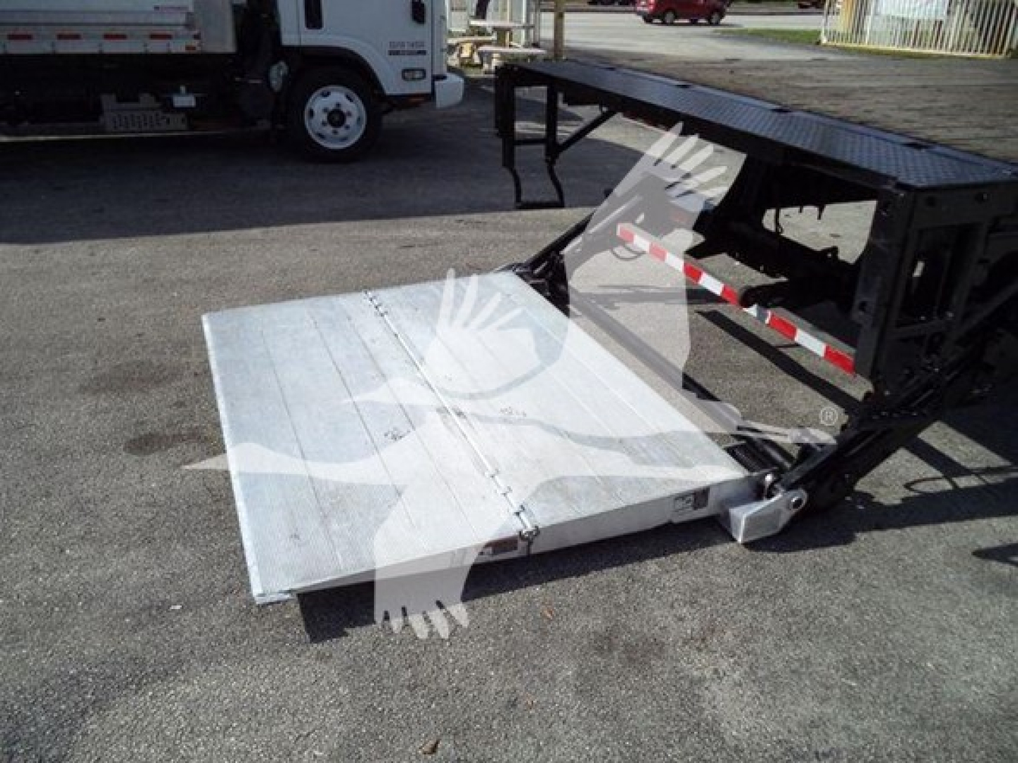 Flatbed truck accessory showing a hydraulic ramp and lifting mechanism with a metal platform extended.