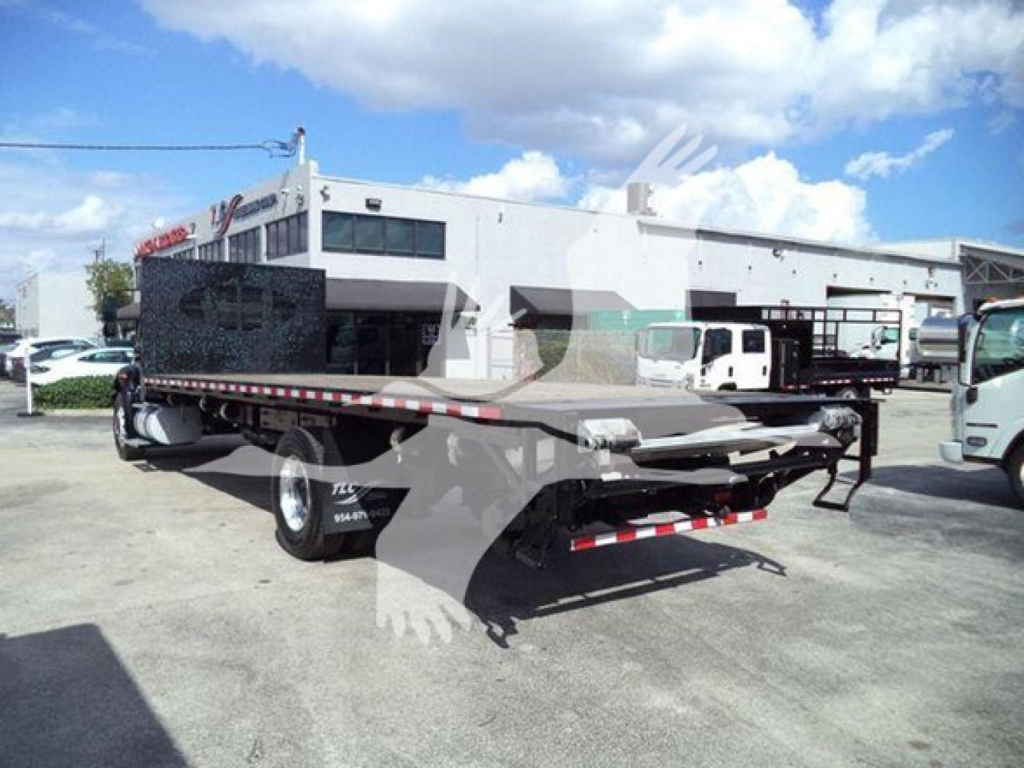 Flatbed truck showing rear view of 2019 International Durastar 4300 with flatbed and towing equipment.