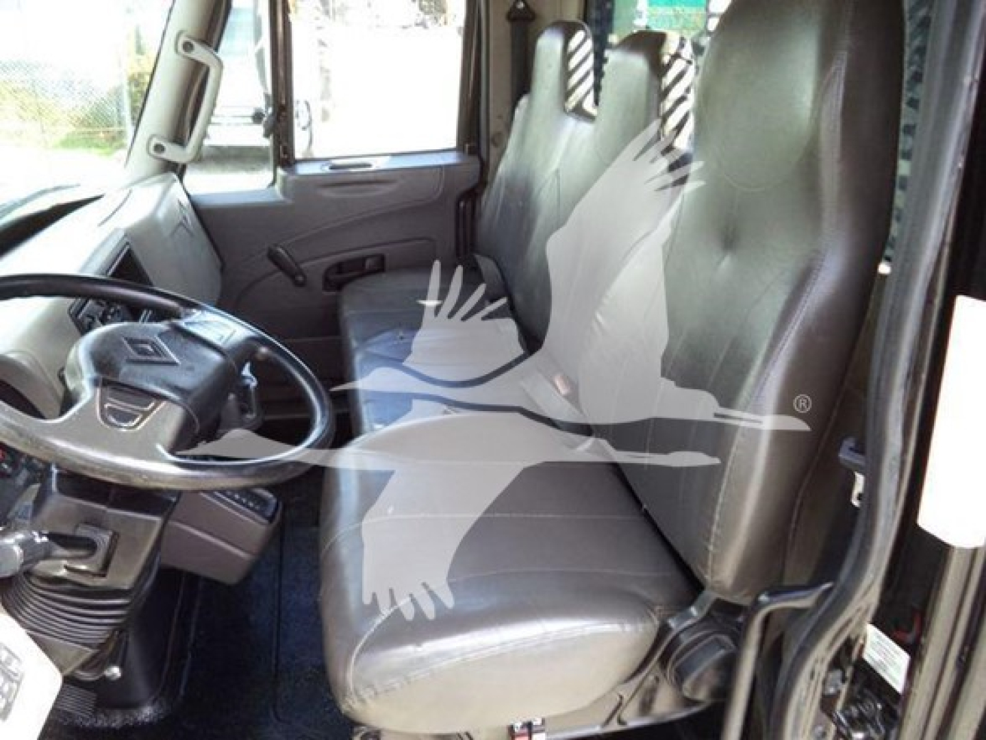 Interior of a 2019 International Durastar 4300 flatbed truck showing front seats, steering wheel, and dashboard. Visible VIN plate and doors.