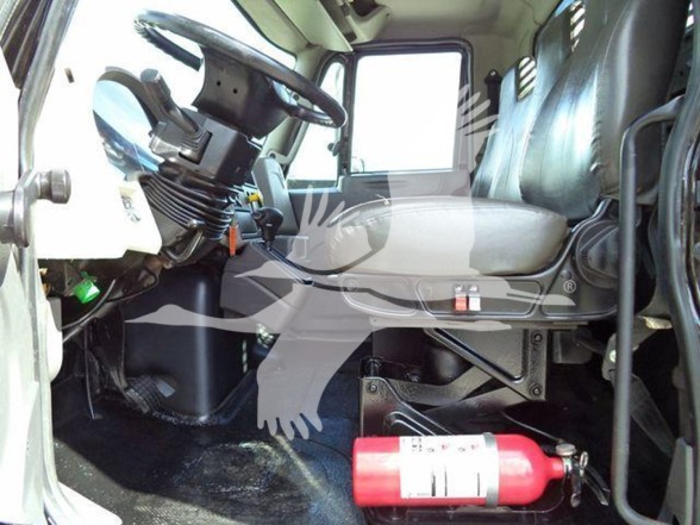Interior of a 2019 International Durastar 4300 truck cab showing driver seat, steering wheel, dashboard, and a red fire extinguisher on the floor near the passenger area.