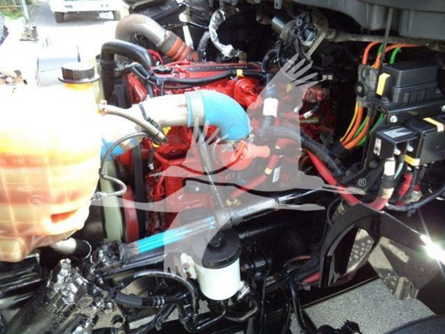International Durastar 4300 engine bay showing red engine, blue hose, coolant reservoir, battery with wiring and various hoses.