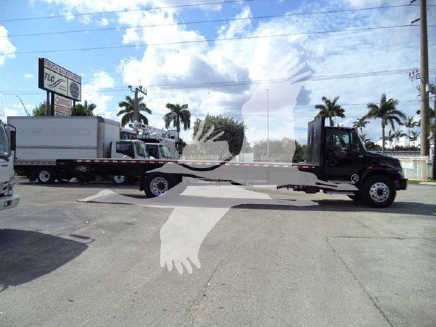 Flatbed tow truck with a long wheelbase International Durastar 4300, black cab, white flatbed, two rear axles, VIN 1HTMMMML5KH584209, stock T84209.