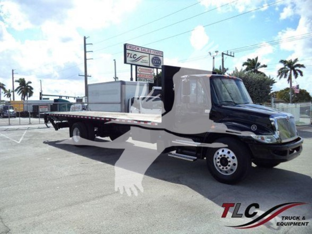 International Durastar 4300 flatbed truck in service view showing cab and flatbed with DMV background and dealership sign.