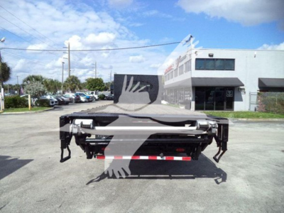 Flatbed truck bed rear view of a 2019 International Durastar 4300 with hitch and equipment in a dealership lot.