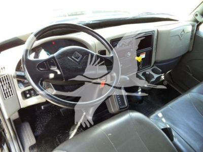 Truck interior showing steering wheel, dashboard, and center console of a 2019 International Durastar 4300 with a flatbed configuration.