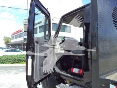 Truck cab interior with open door showing dashboard and seating in a flatbed truck.
