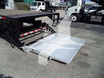 Truck flatbed equipment showing a deployable aluminum ramp and flatbed frame with reflective tape; International Durastar 4300 listing.