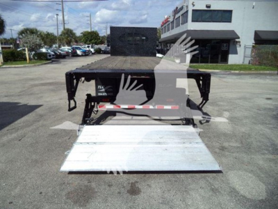 Flatbed tow truck chassis with deployable aluminum ramp extended, International Durastar 4300 platform; visible label 764 C-? room; dealership lot in background.