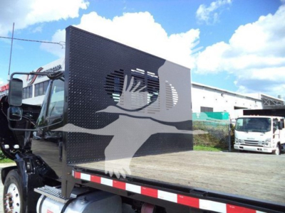 Flatbed truck with a black aluminum headache rack featuring a gray dove graphic in the cargo area; International Durastar 4300 style cab visible on left.