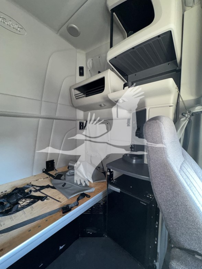 Peterbilt cab interior showing dash area and sleeper side with overhead compartments and a swivel seat in gray fabric.