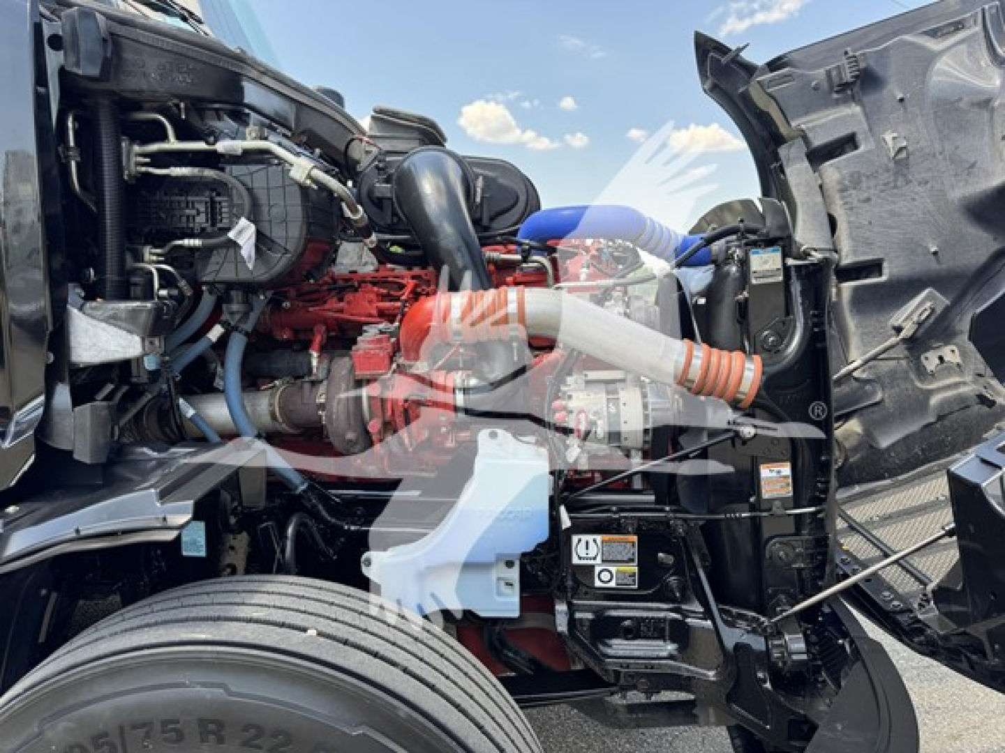 Peterbilt 579 engine bay with visible turbo, hoses, and battery; front wheel and engine components in view.