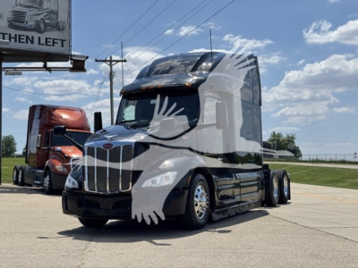 Peterbilt 579 conventional sleeper tractor in white and black, front view with chrome grille and aerodynamic mirrors.