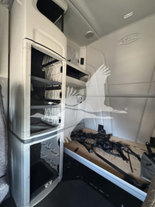 Peterbilt 579 truck cab interior showing open storage compartments and sleeper area with built-in shelving.