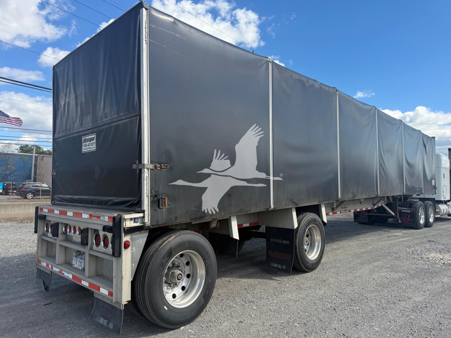 Trailer side view showing Maxmiser curtainside with gray tarps and white crane logo, rear bumper, dual rear axles, and stock number PC-8724.