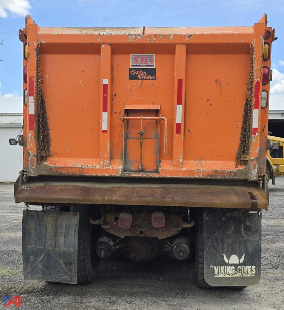Dump truck bed of an International WorkStar 7600 with plow setup showing rear view, orange cargo bed, bumper, mud flaps, and frame.
