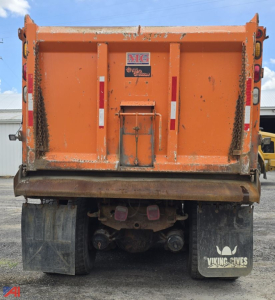 Dump truck bed of an International WorkStar 7600 with plow setup showing rear view, orange cargo bed, bumper, mud flaps, and frame.