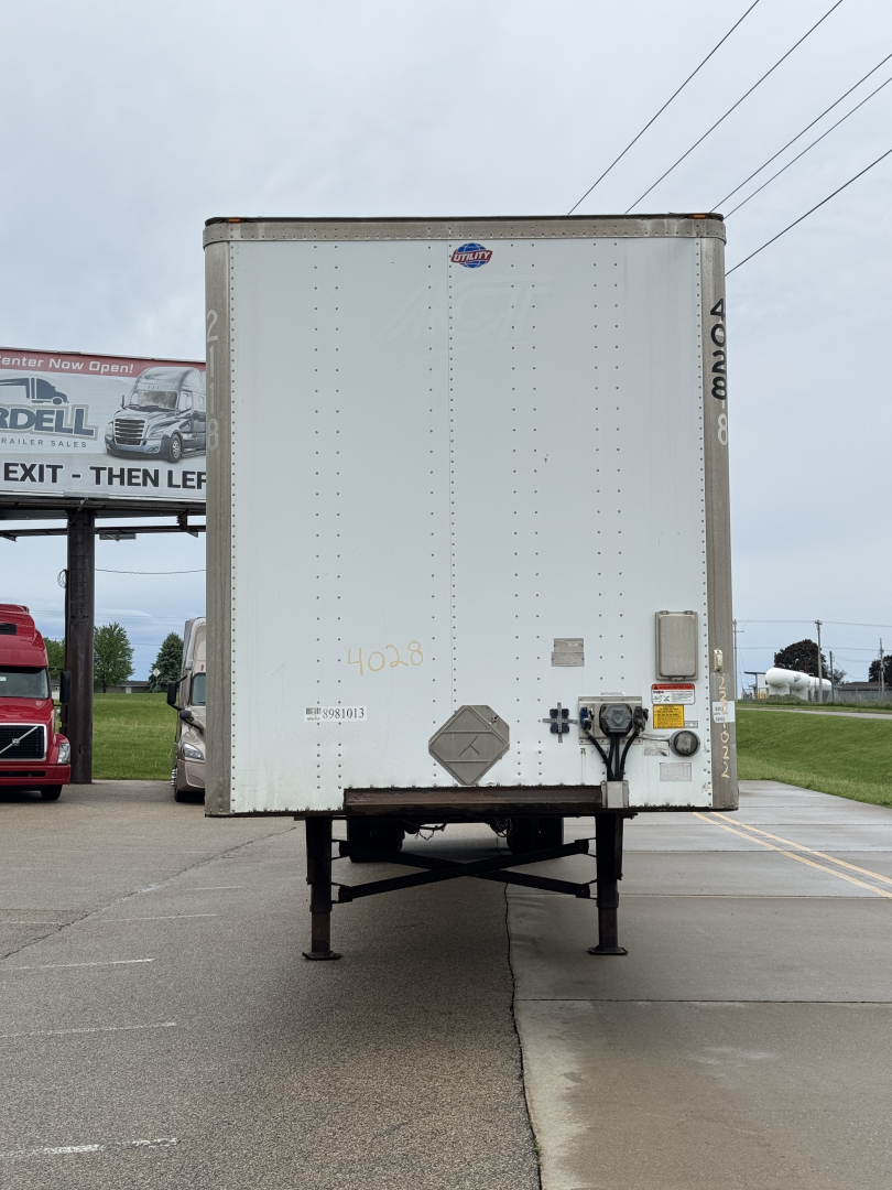 Rear view of a 2014 Utility 4000DX trailer showing bumper and hitch, with VIN and stock number markings faintly visible on the door.
