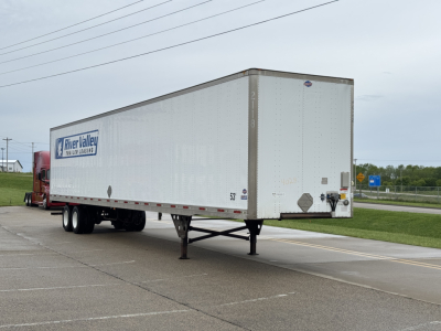 Trailer side and rear of a 2014 Utility 4000DX with River Valley logo, dual rear doors, rear legs extended, and highway background.