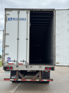 Trailer rear view showing cargo area with open doors and River Valley Transportation logo, taillights, and license plate.