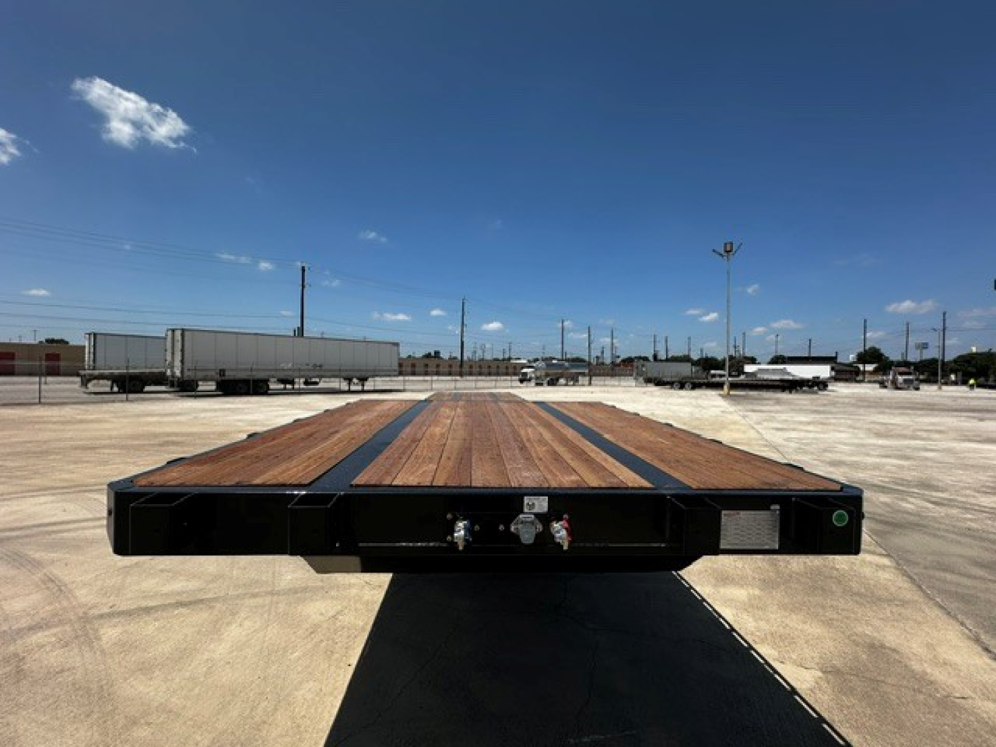 Trailer deck showing 48-foot drop deck with wooden planks and steel frame; front coupler area visible with connectors.