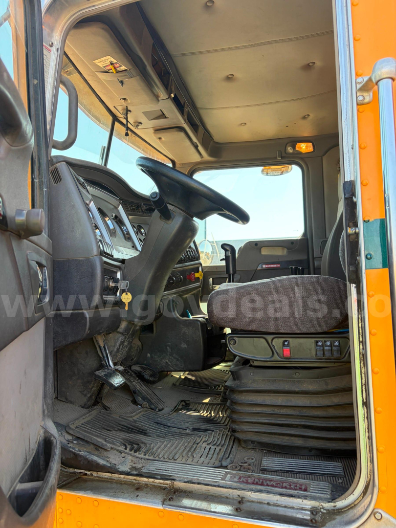 Cab interior of a 2008 Kenworth T800B dump truck showing driver seat, steering wheel, and dashboard from the doorway.