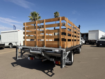 Chevrolet 4500 flatbed truck with wooden stake sides and rear-view showing stock number 7906 at a dealership yard.