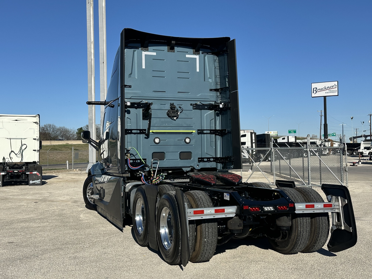 Tractor trailer rear view showing the back of the cab, with fifth wheel and dual rear axles, no visible text other than small decals on components.