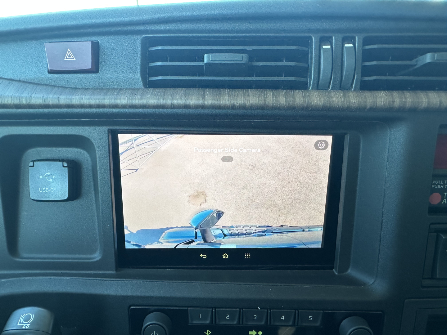Dashboard display showing a rearview camera screen in Volvo VNL cab with surrounding vents and control switches.