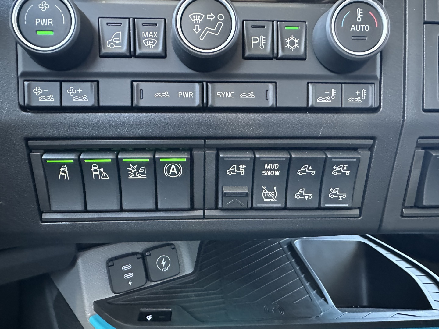 Volvo VNL dash panel showing multiple switches with green indicators and circular climate controls visible.