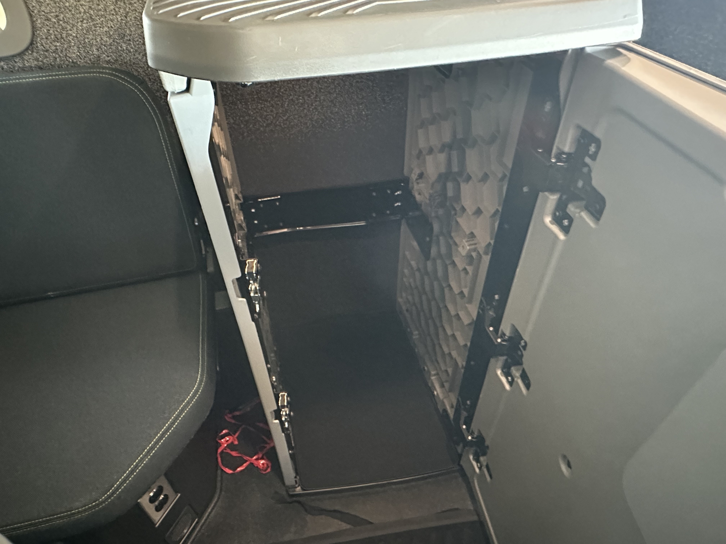 Truck cab storage compartments open showing under-seat cabinet with dark interior